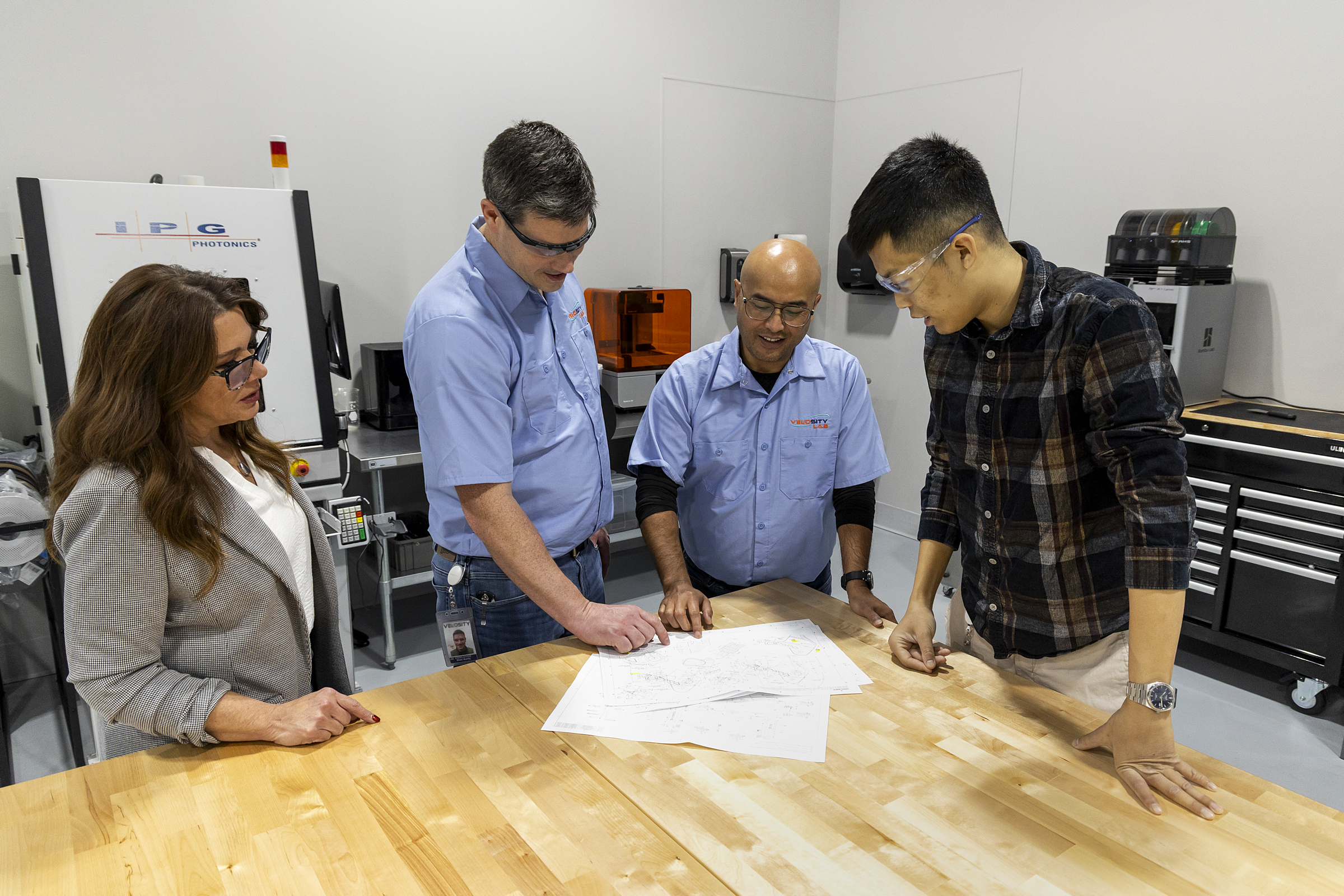 A group of Velosity employees gather around a table to look at plans.