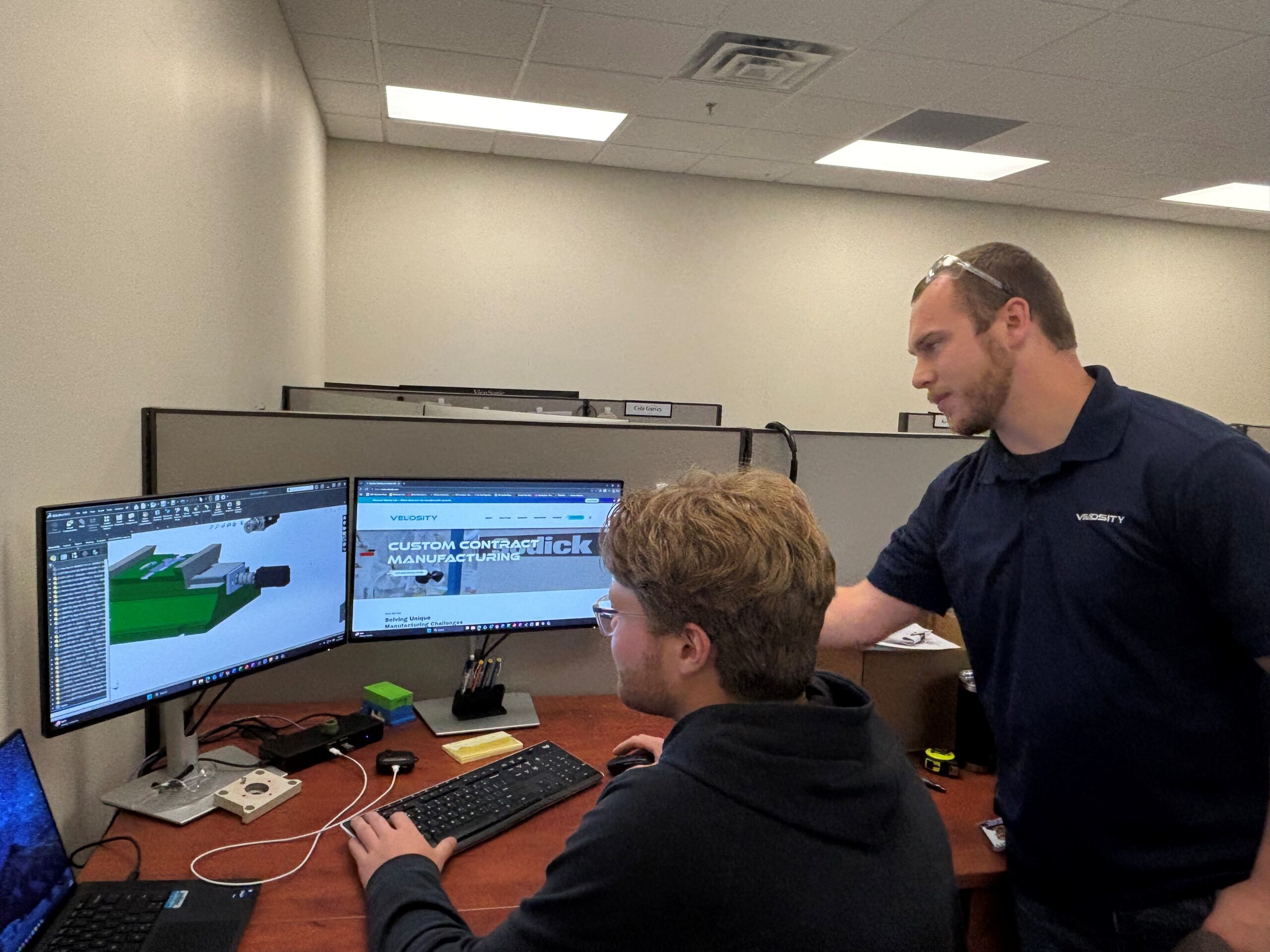 Two Velosity employees gather around a computer