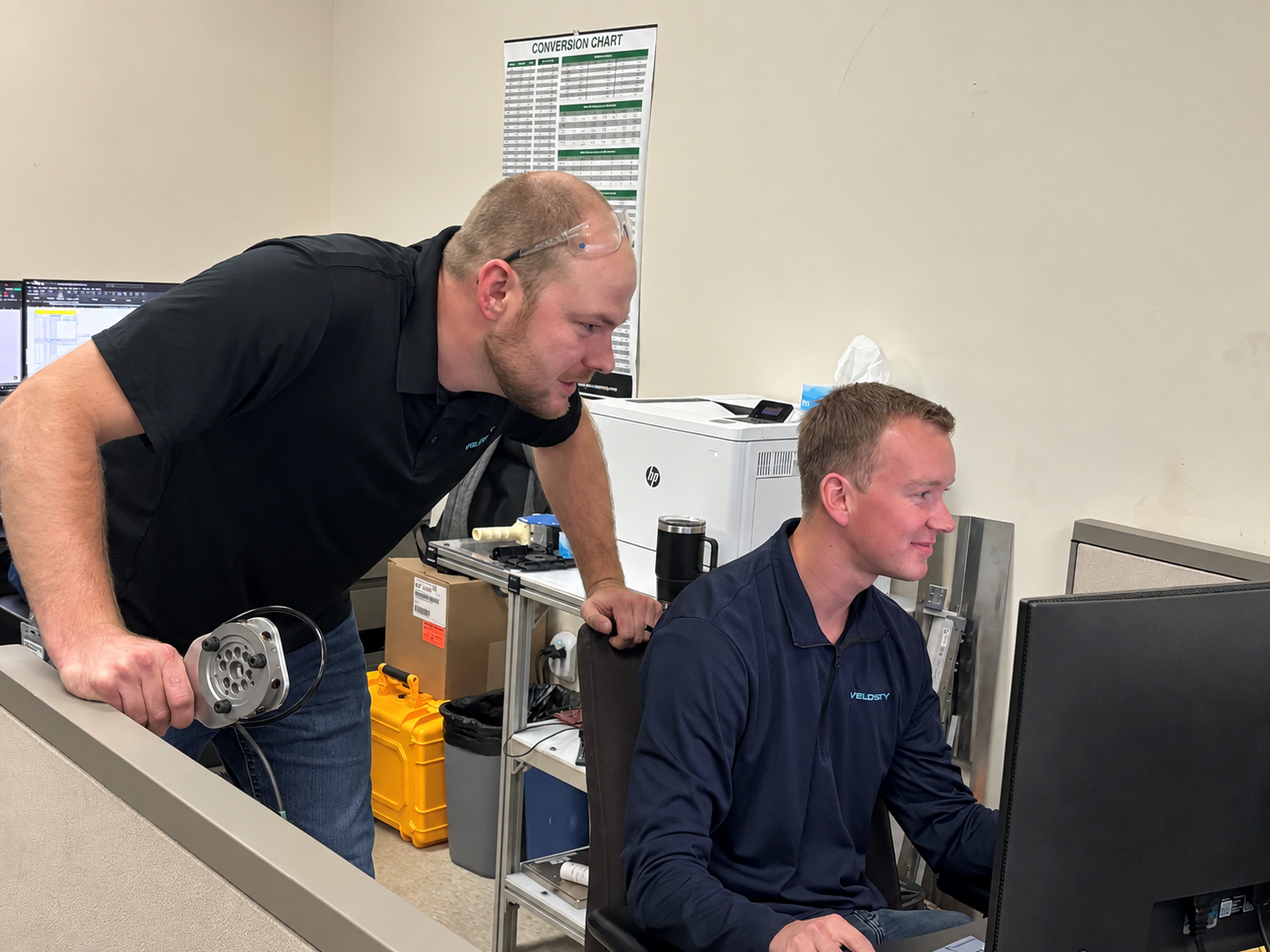Embedded Engineering Fixture Design Updated Velosity employees gather to look at plans