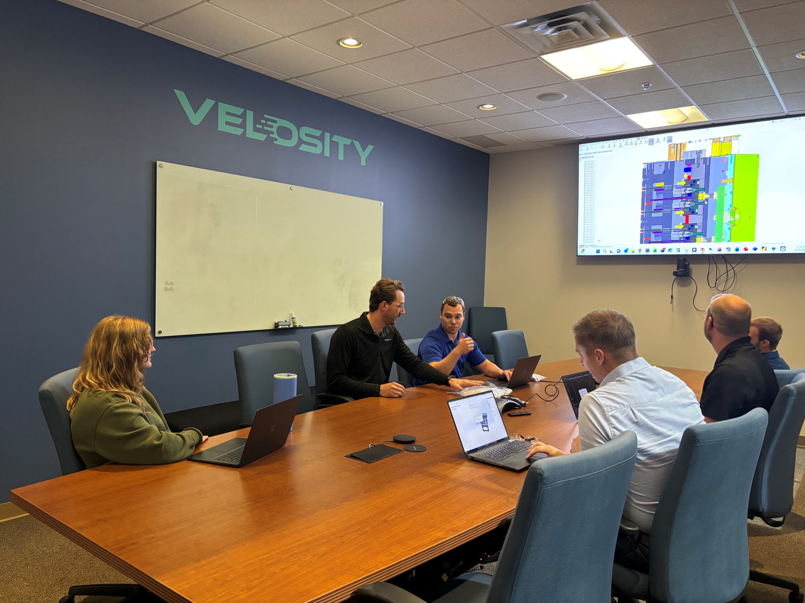 Velosity_Embedded_Engineering_Mechanical_Engineering_no_glare Velosity employees gather to look at plans